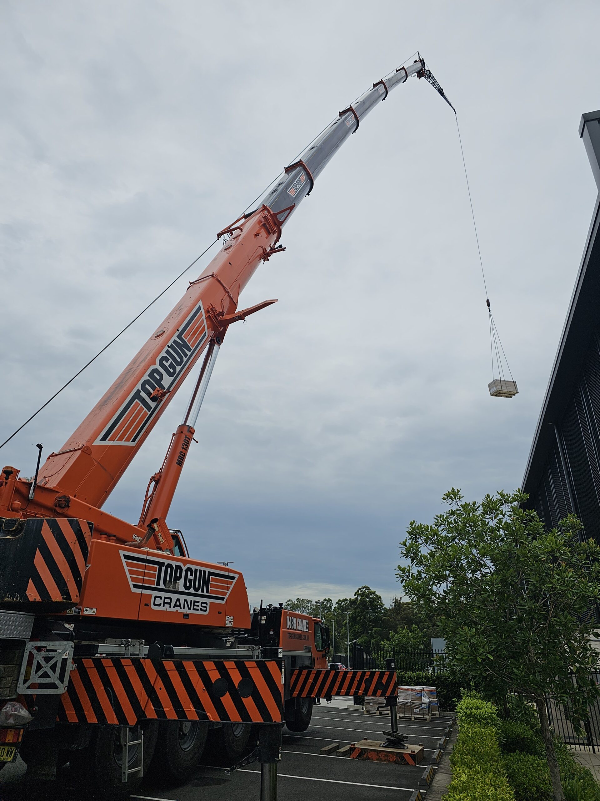 A large red crane lifts a wooden crate in the car park of the FMCCC. 