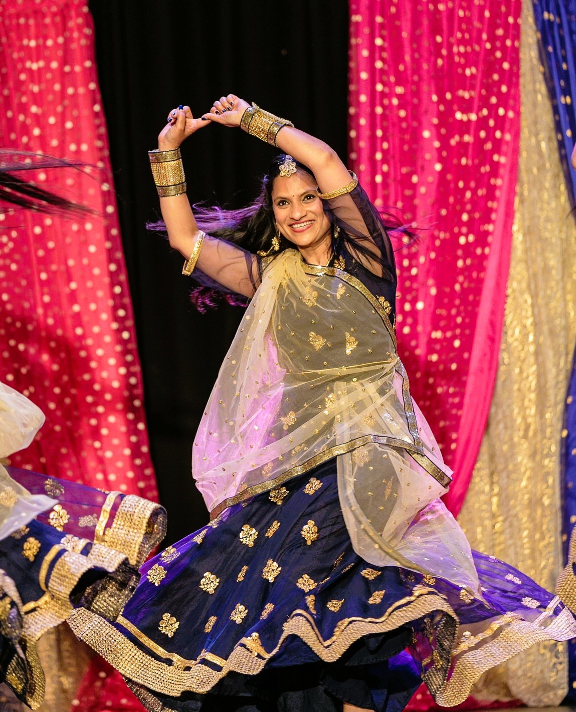 A woman dancing with her arms raised, wearing a traditional Indian-style dress.