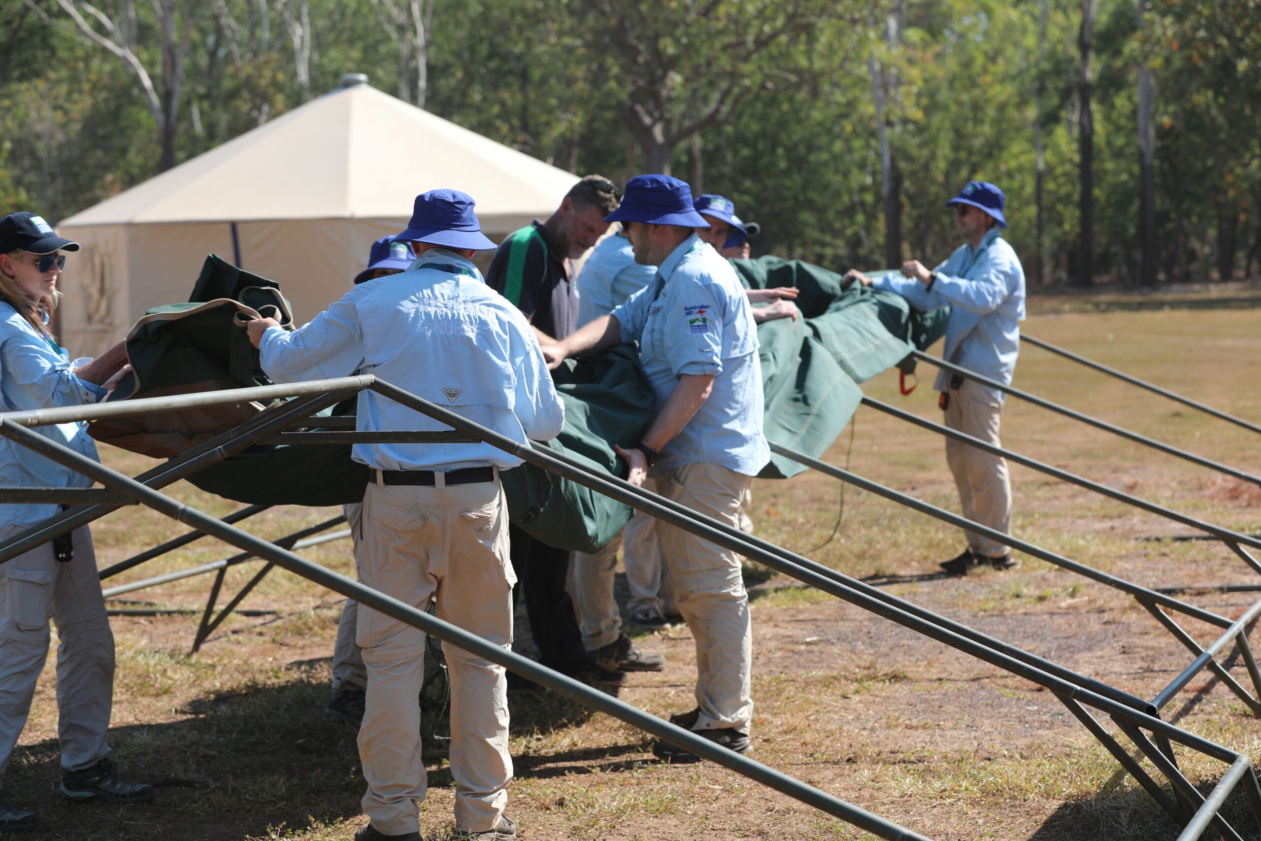 A group of people setting up a field tent.