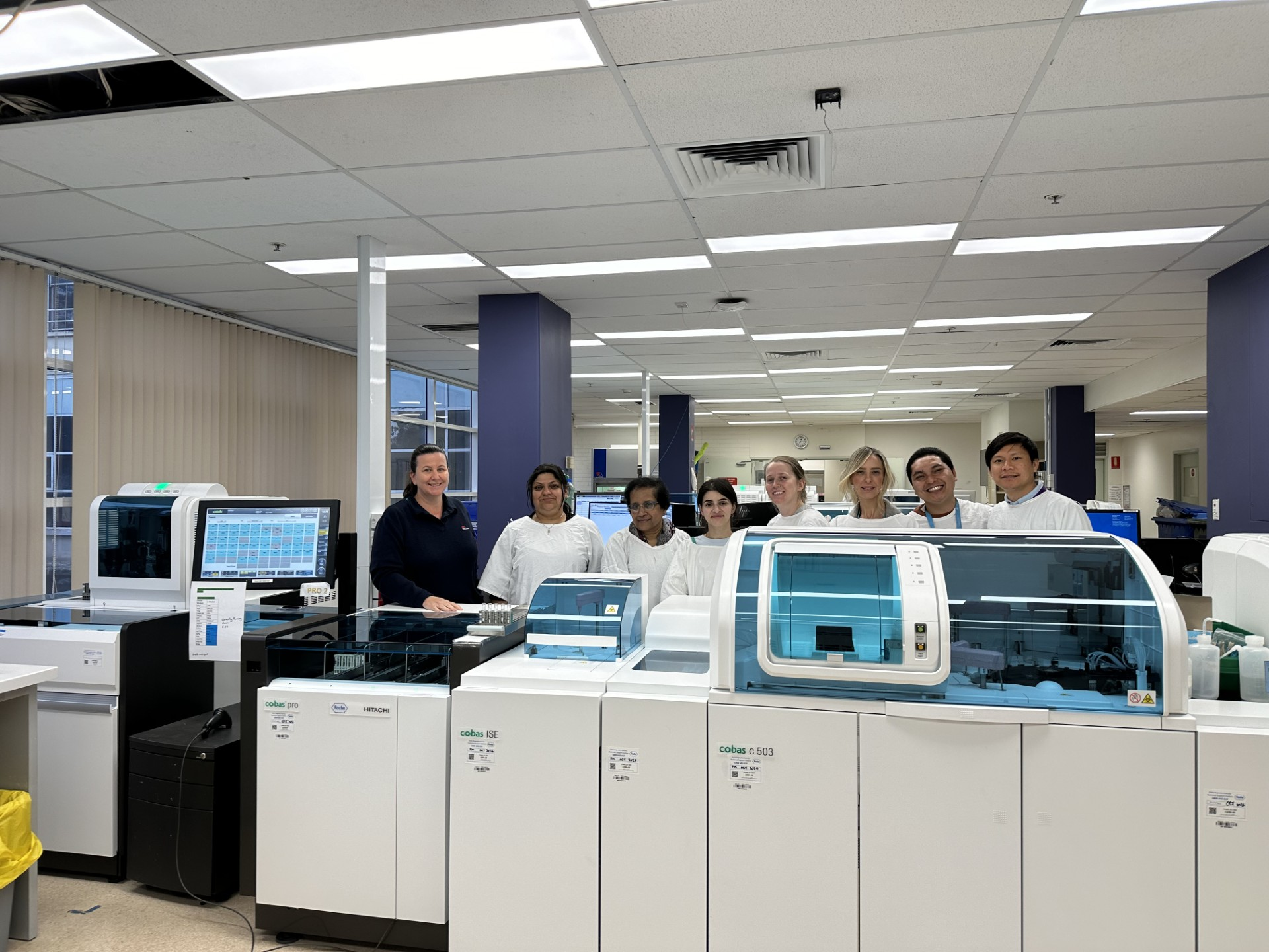 people in lab standing in front of machine