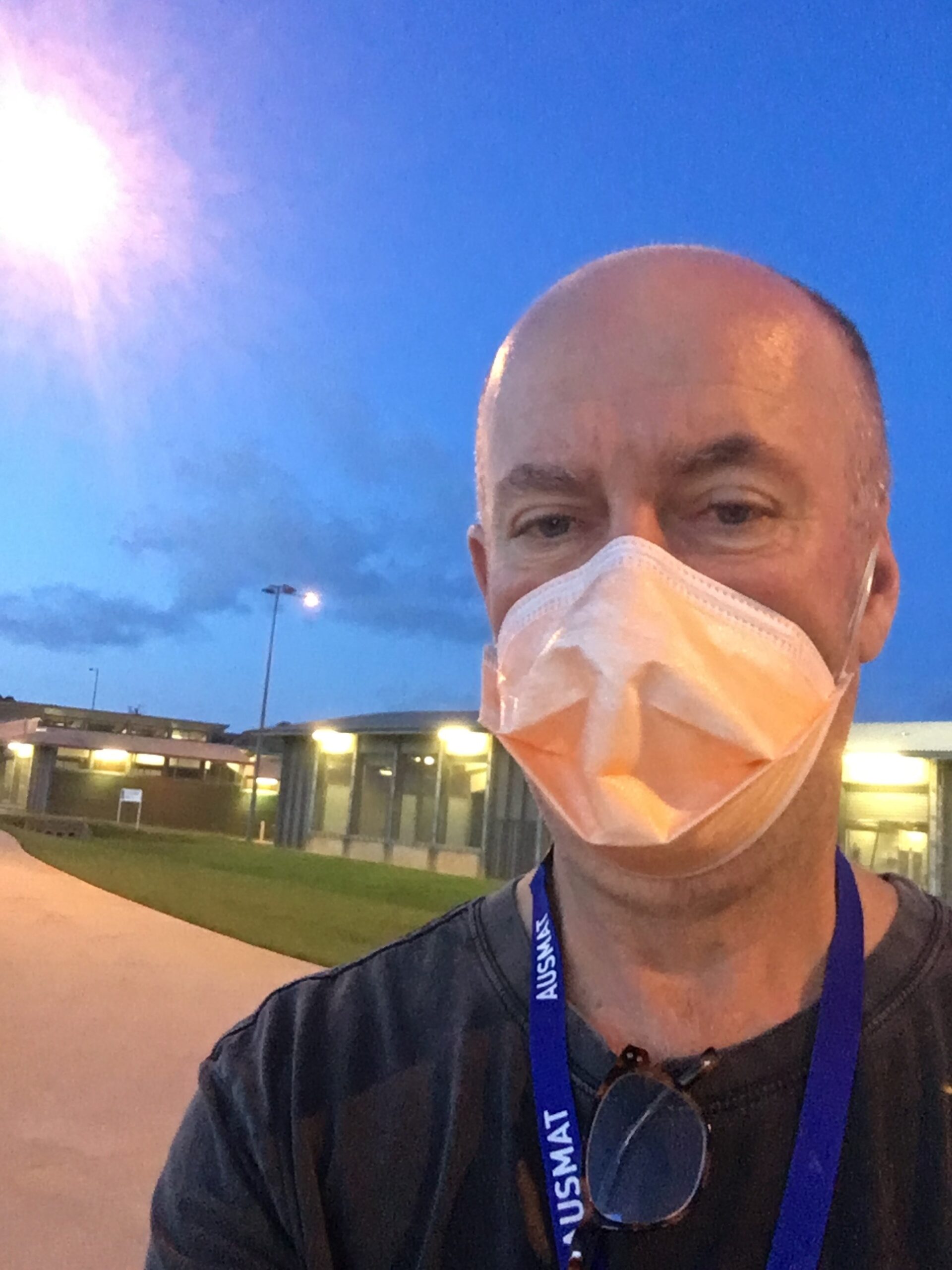 A man wearing a face mask taking a selfie at a quarantine facility.