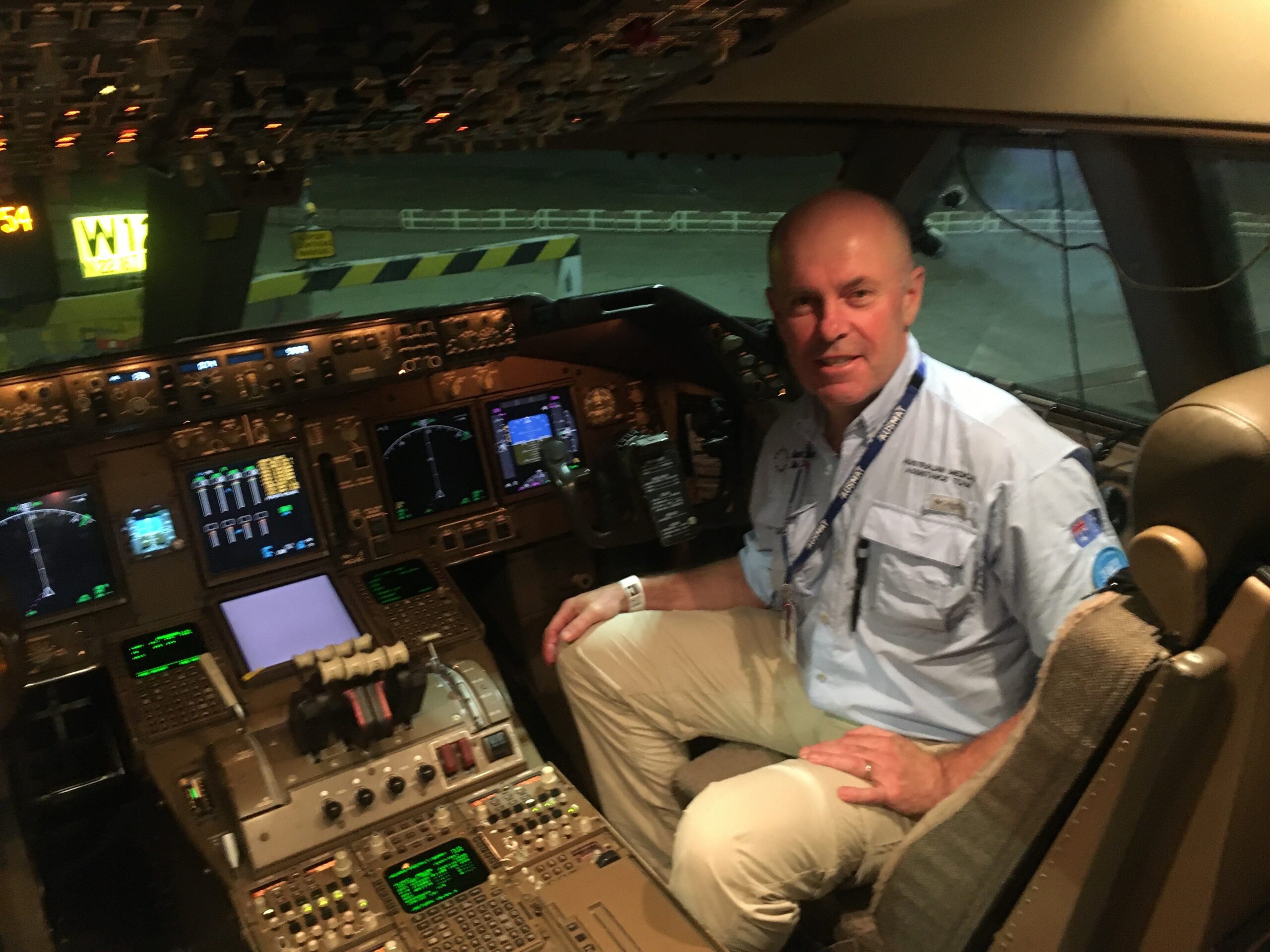 A man sits in the cockpit of a plane wearing an AusMat uniform.