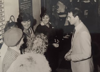 A black and white photo of a group of women smiling at HRH Prince Edward.