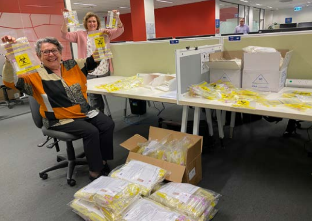 Two women in an office surrounded by packaging.