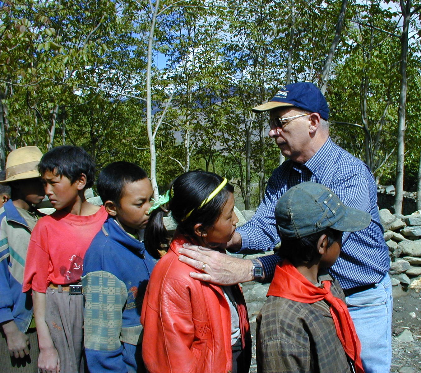 A group of children, with a man examining the neck of one child.