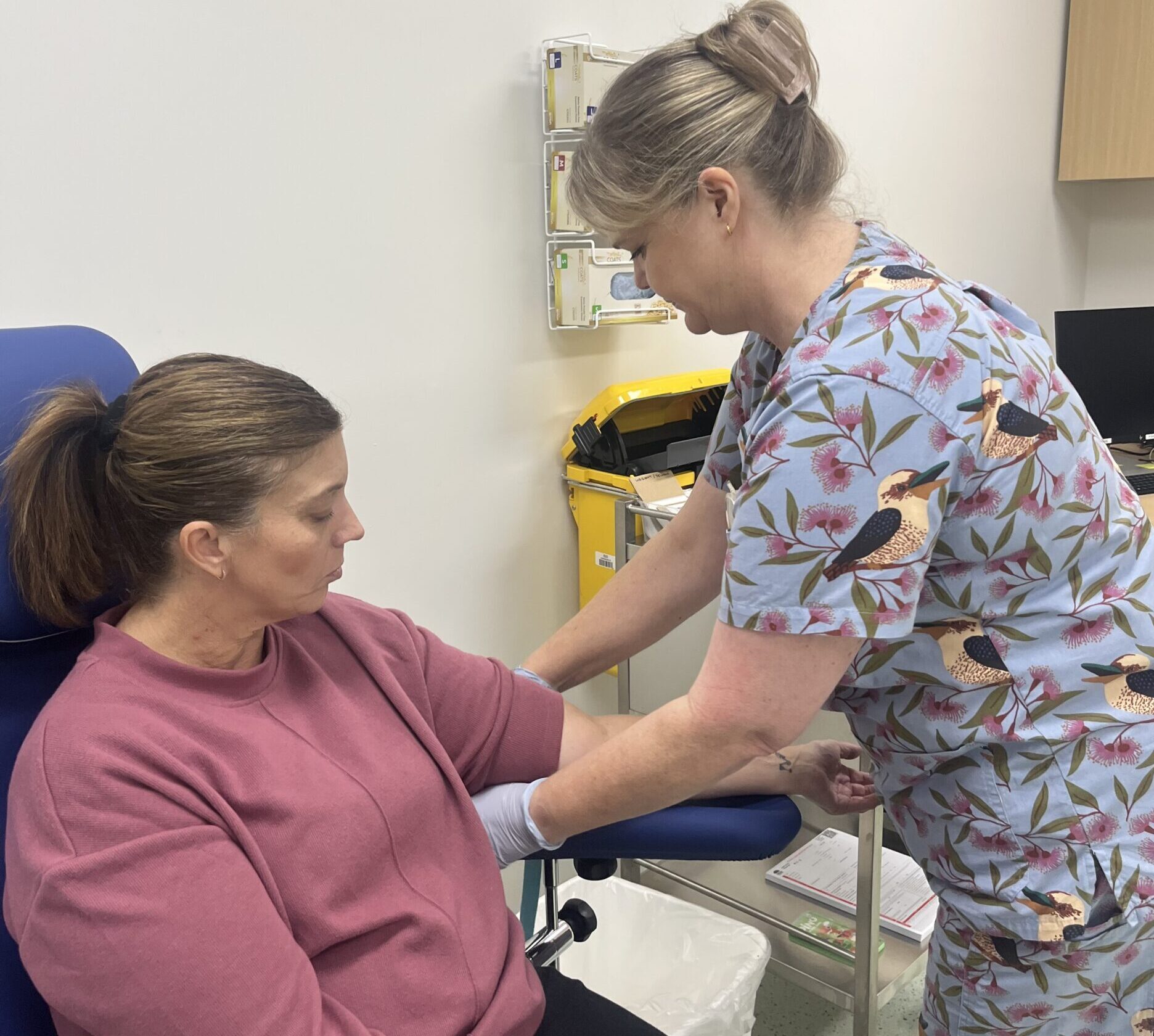 Come and see us at our new collection service at Charlestown! 1 A woman wearing brightly coloured healthcare scrubs taking a blood sample from a woman.