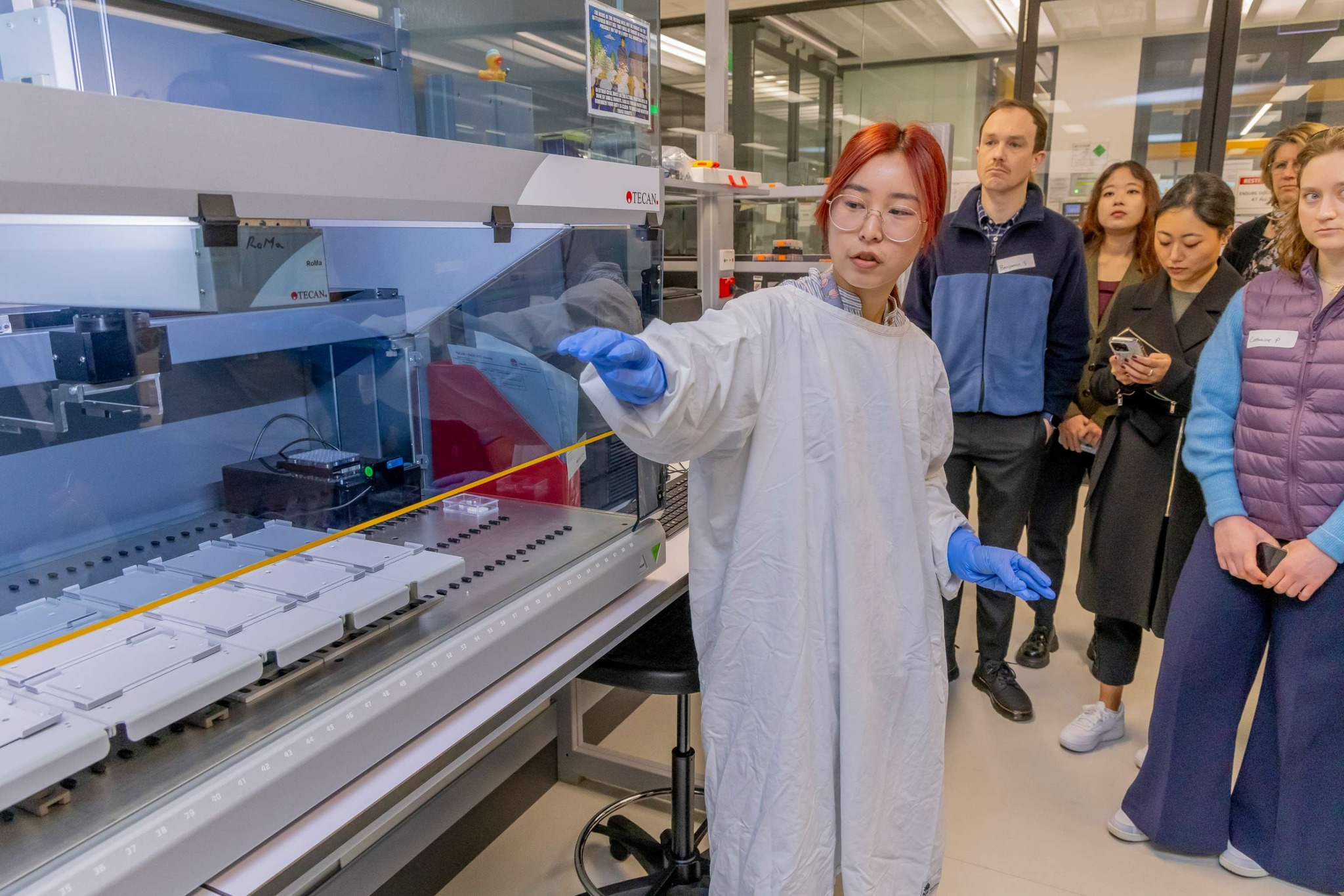 Take a look inside the NSW Health Statewide Biobank 3 A woman in a white lab coat shows a group of people some of the high-tech equipment at the Biobank.