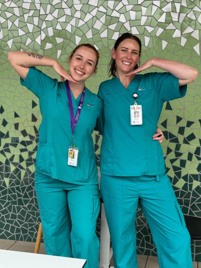 Two ladies in green scrubs smile for the camera