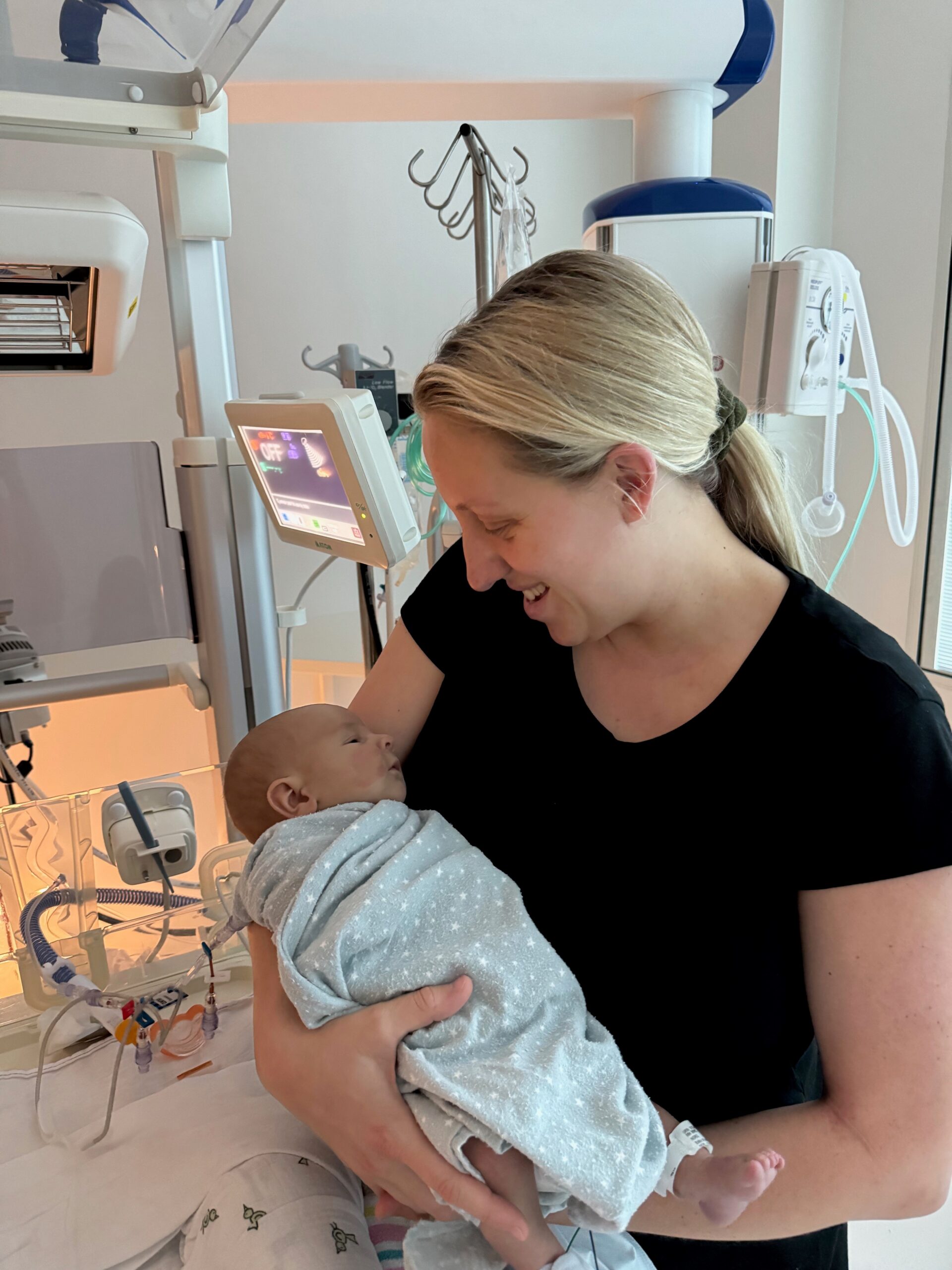 A woman holding a newborn baby in a hospital room. 