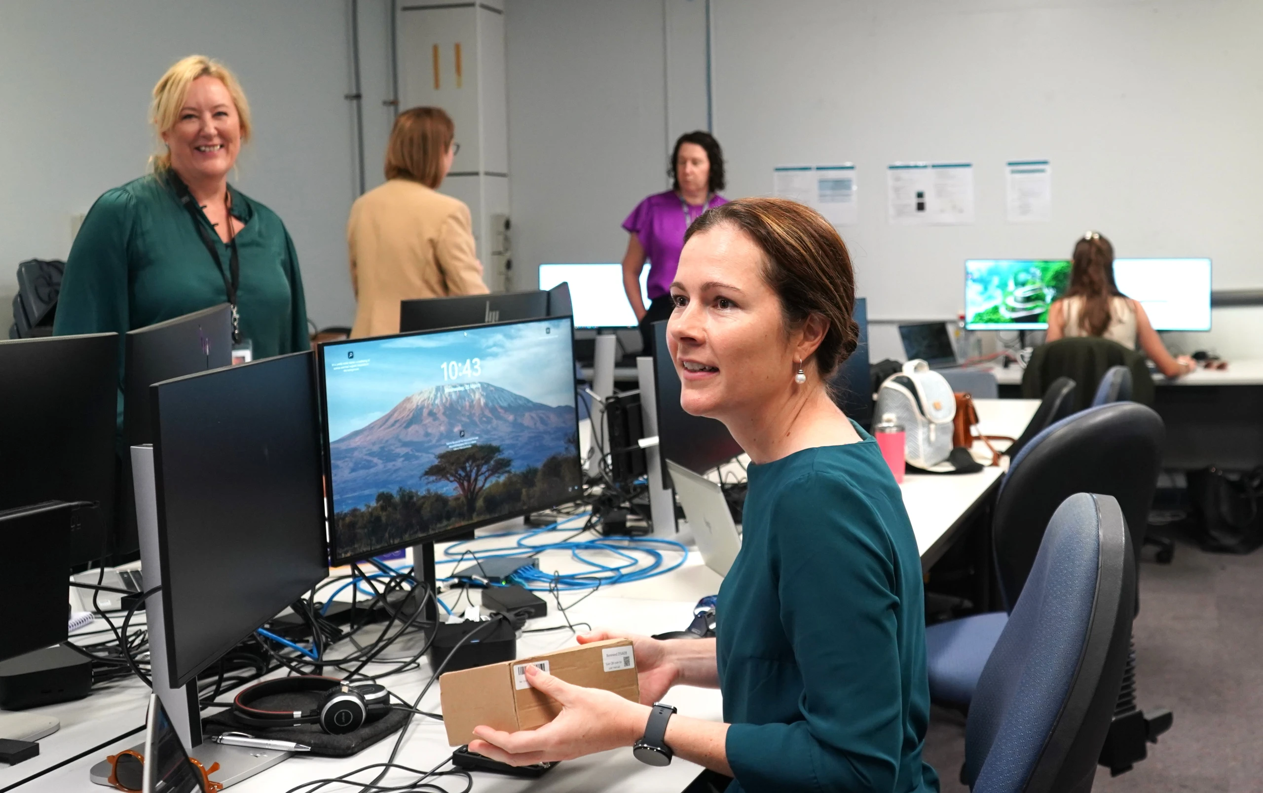 A woman at a desk with several others behind her working.