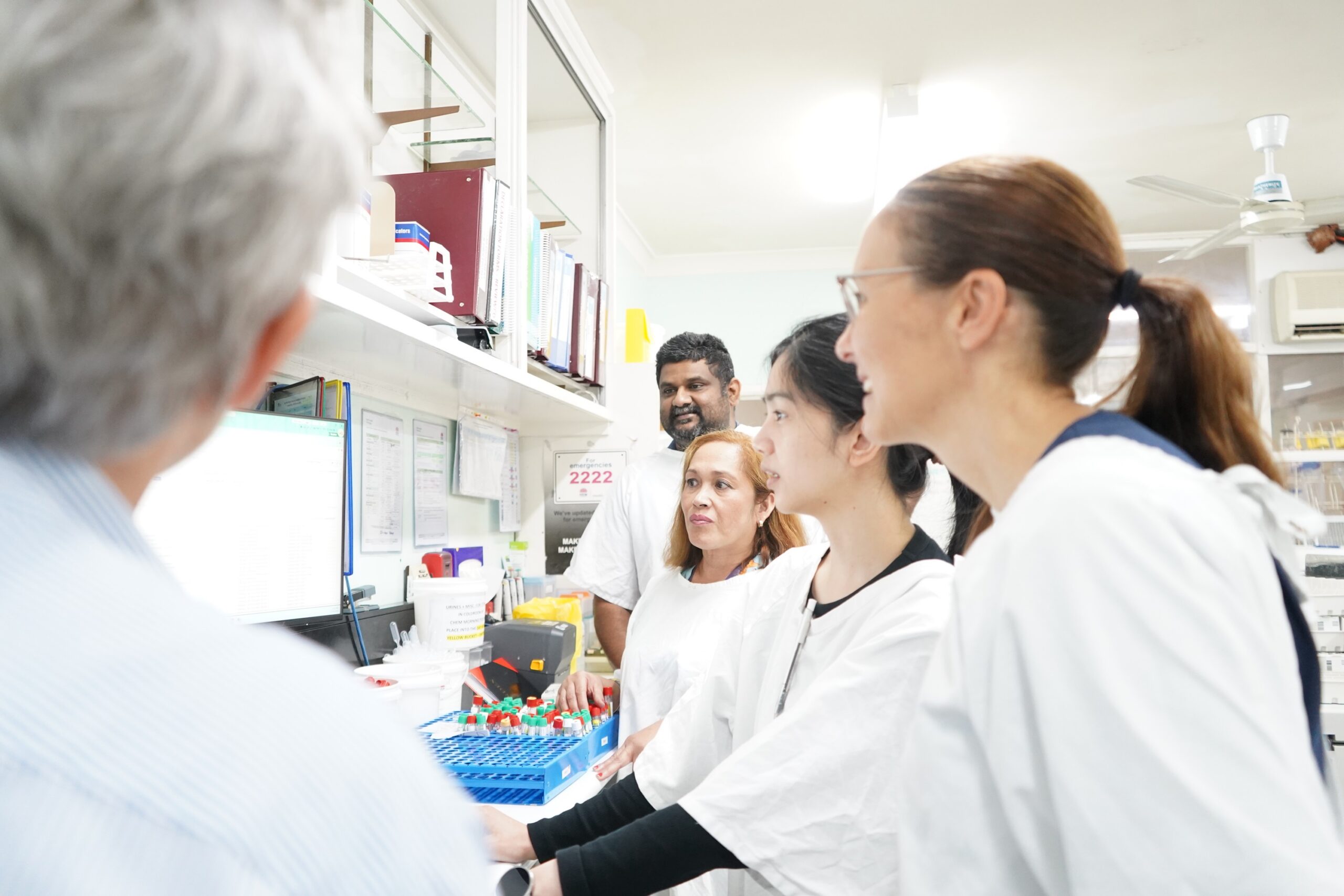 Laboratory staff look at a computer screen.