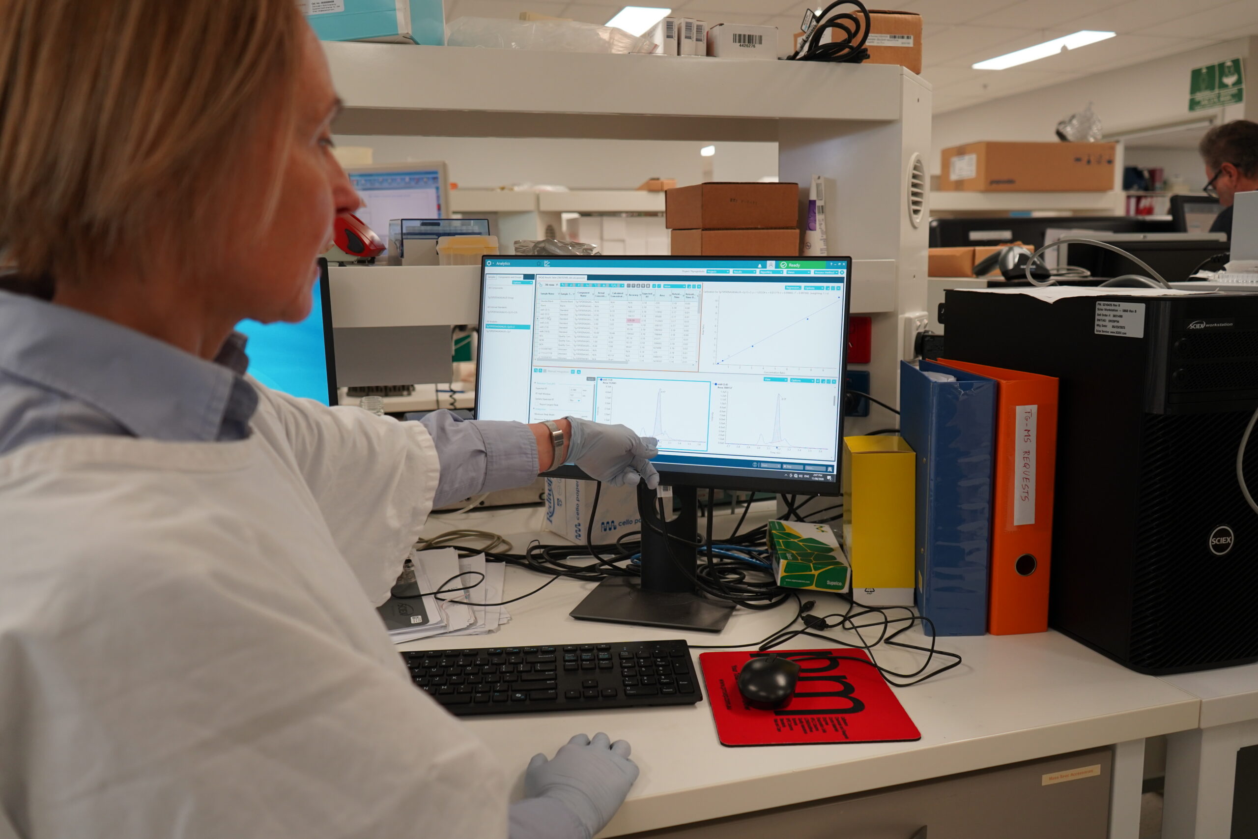 New Australia-first test offers advanced monitoring for thyroid cancer patients 2 A woman in a white lab coat in a laboratory points to a series of results on a computer screen.